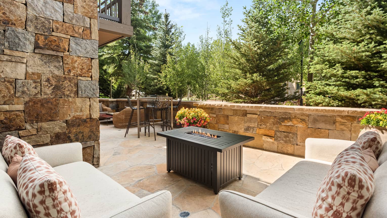 A sitting area outside with two sofas and small fire.