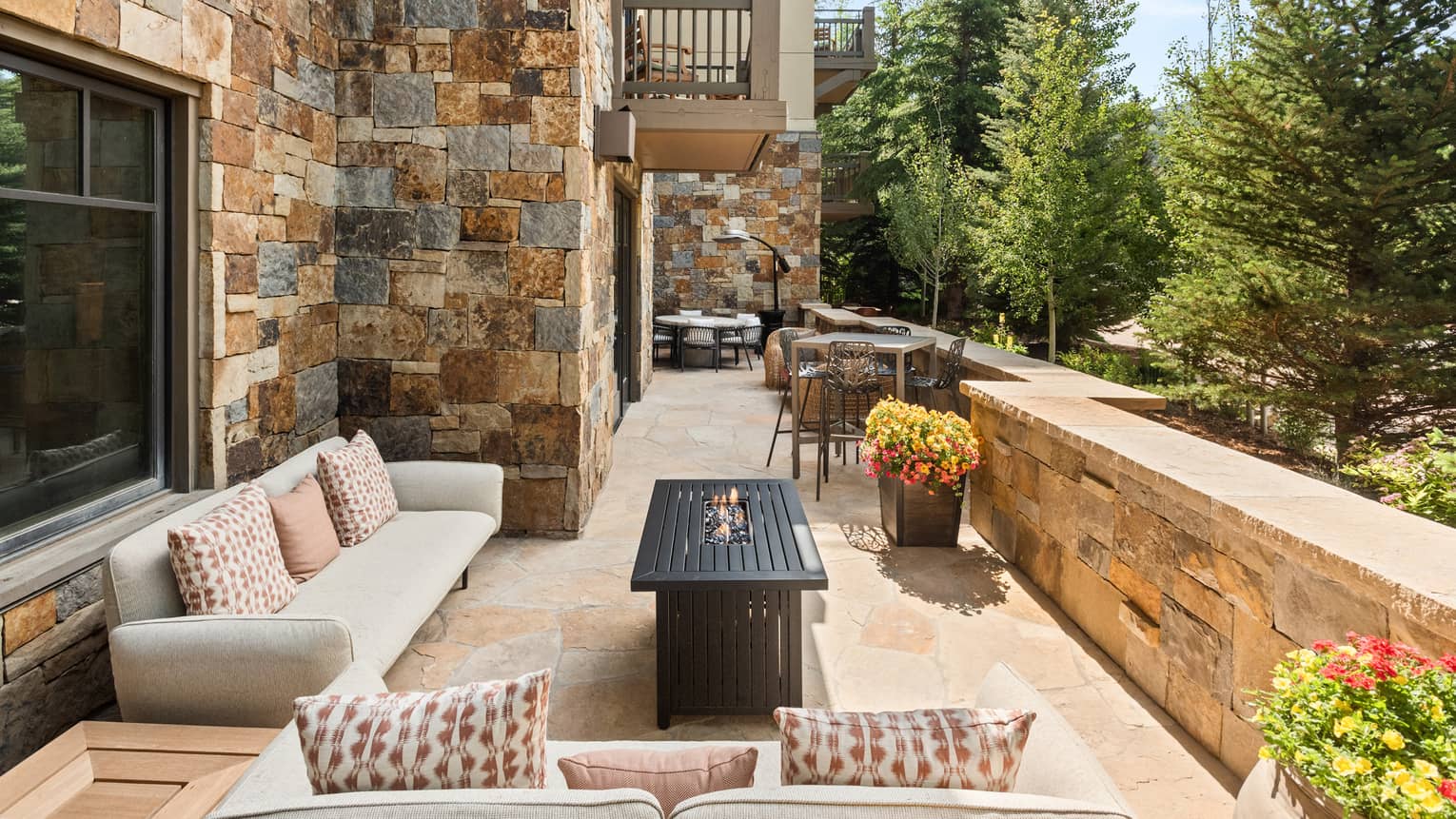 A sitting area outside with two sofa, and small tables and chairs next to them.
