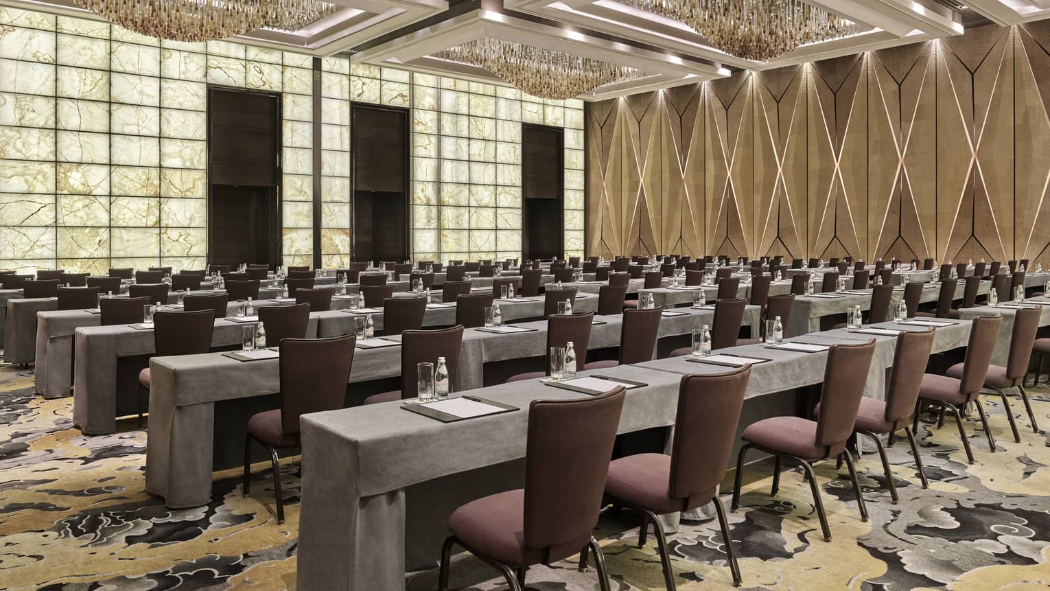 Brightly lit meeting room set up classroom style with rows of burgundy chairs