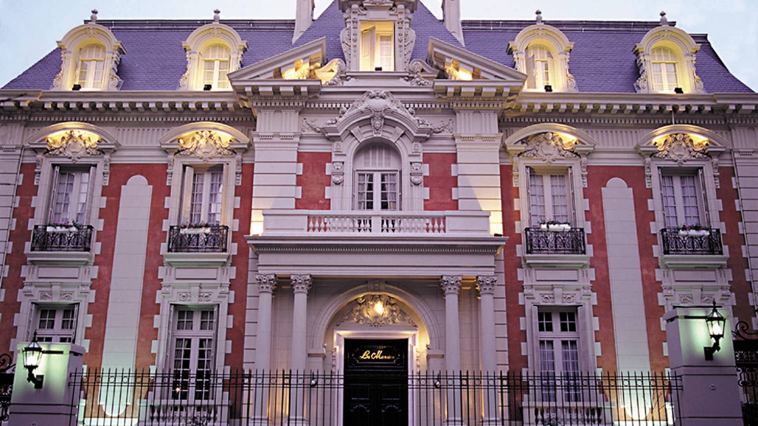 Four Seasons Buenos Aires hotel La Mansión historic exterior with lights at dusk, black fence in front