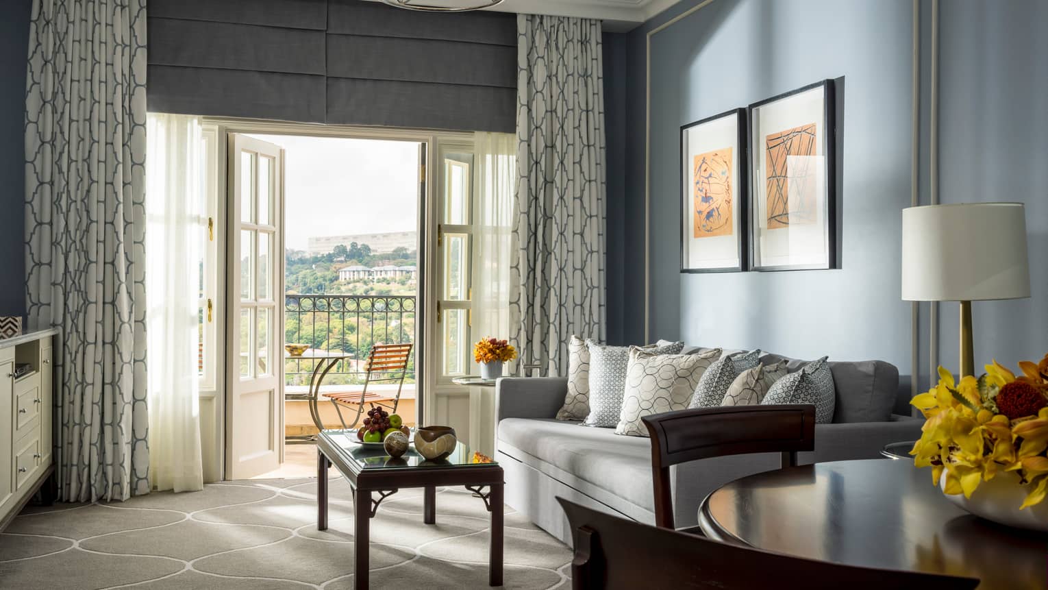 Panoramic-View One-Bedroom Suite round dining table, sofa and coffee table near open French doors to sunny balcony