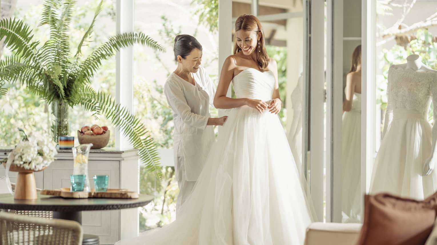 Wedding tailor helps bride in her wedding dress