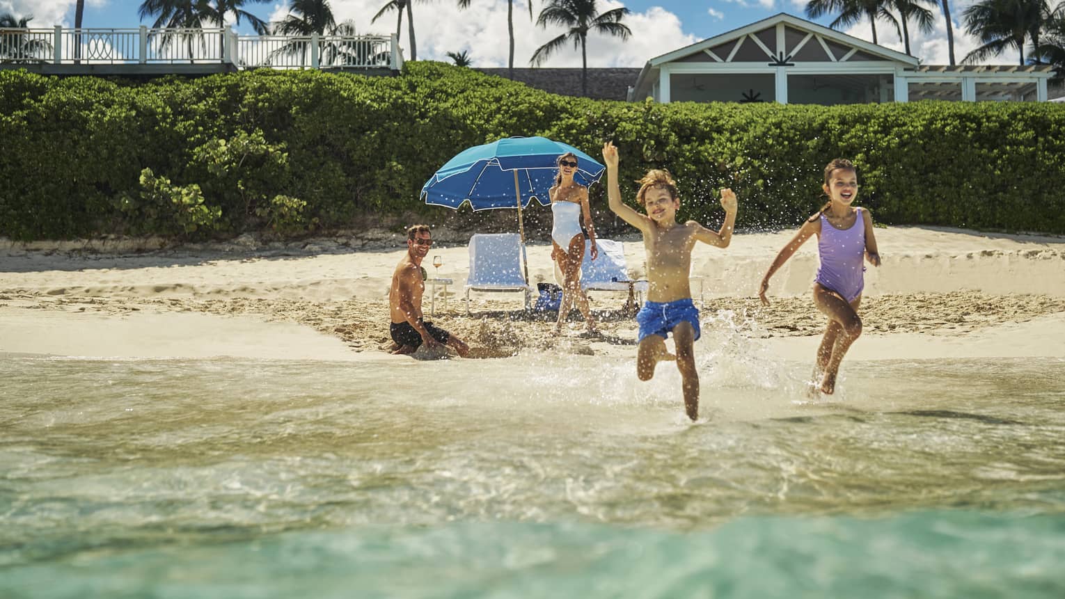 Children playing in the ocean water while parents watch from the sand.