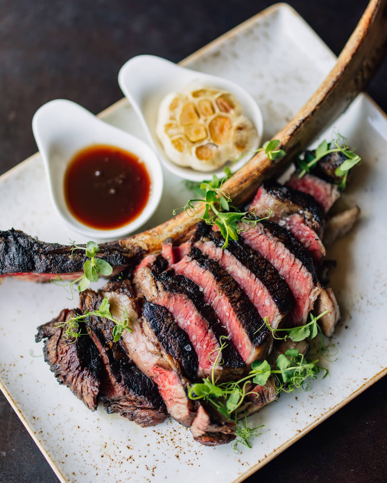A steak sliced off the bone on a white plate.