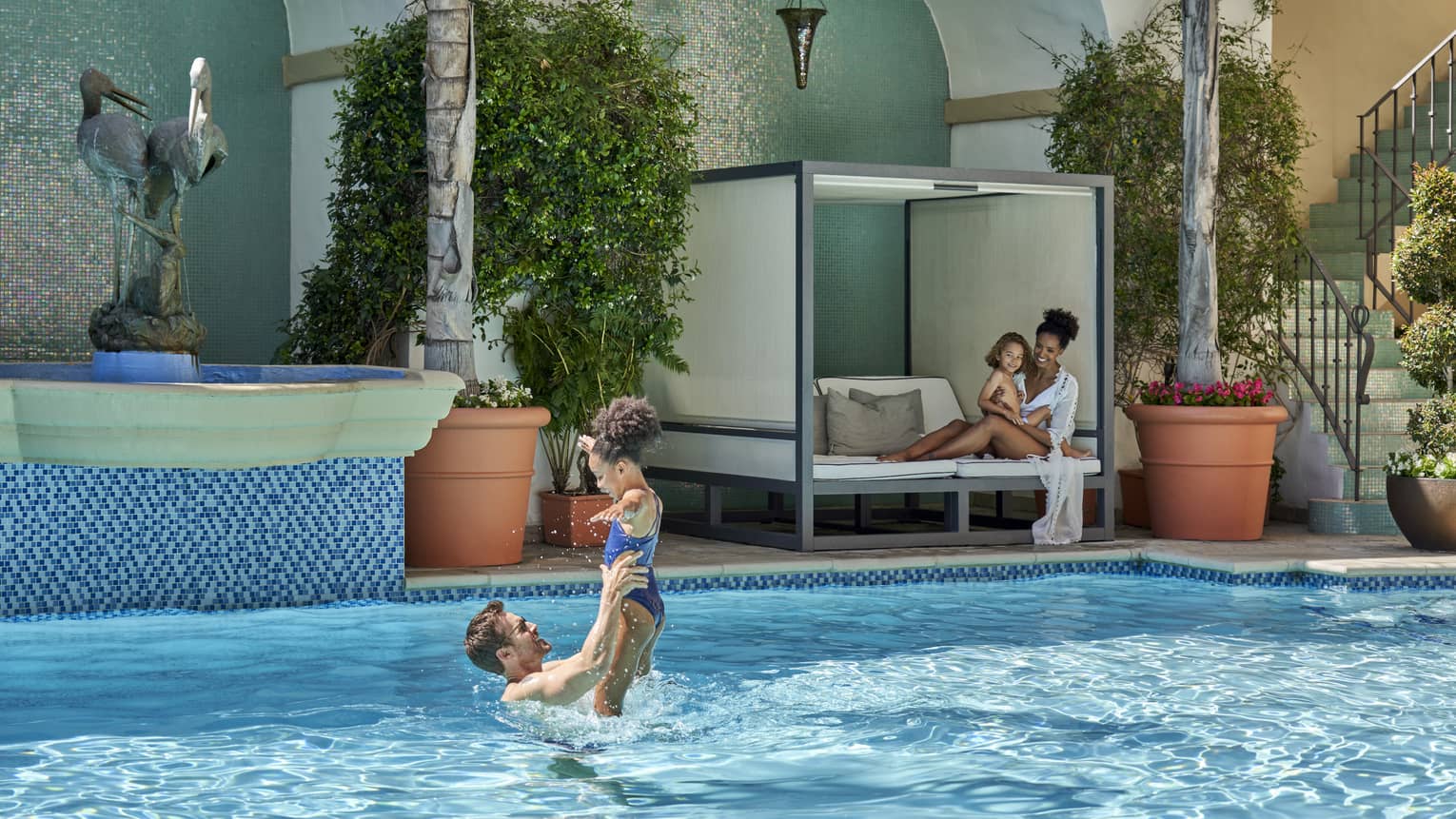 A family playing and sitting by an outdoor pool.