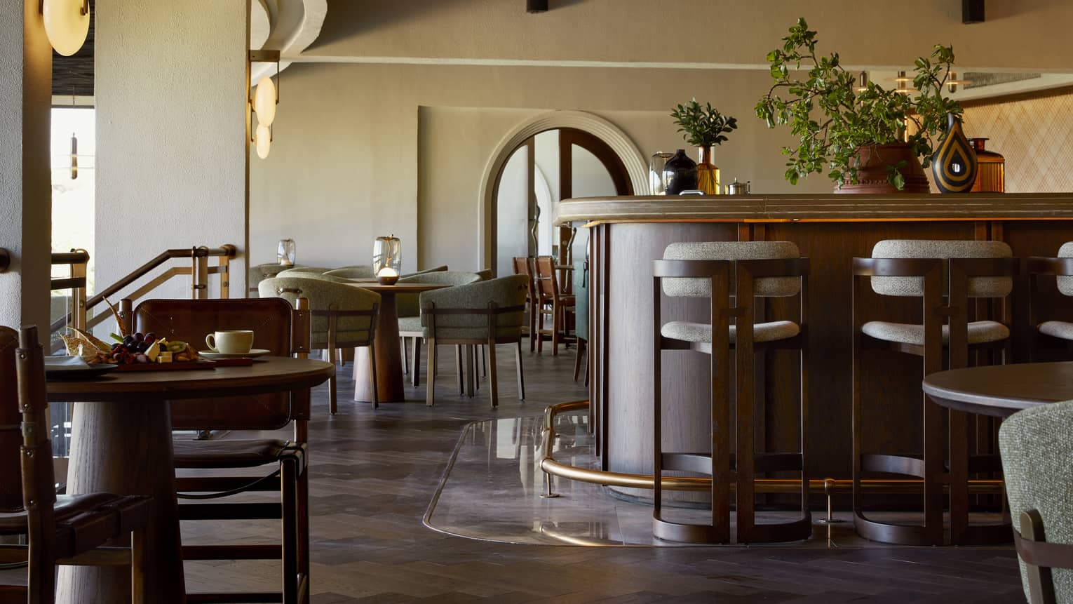Restaurant with rich dark-brown tables and bar with high ceilings and archways
