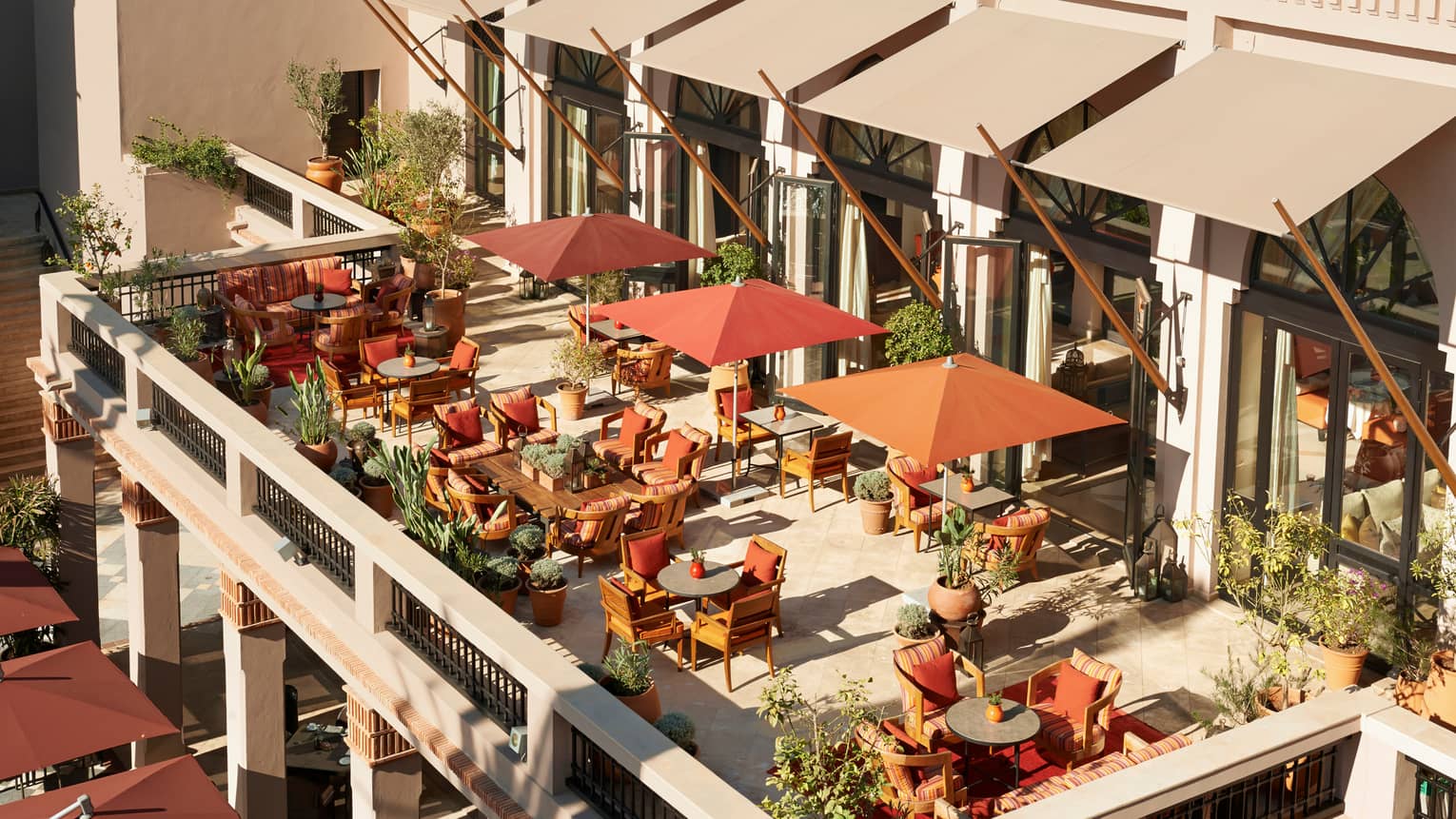Aerial view of sunny patio with dining tables, chairs, orange umbrellas