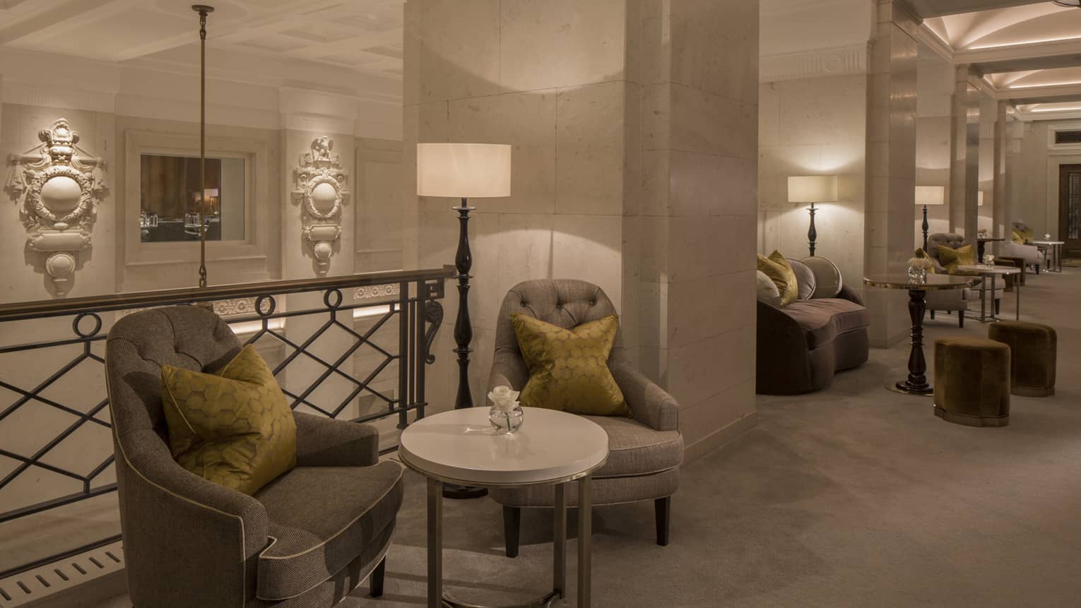 Plush armchairs and cocktail tables by white marble pillars in Gallery Area 