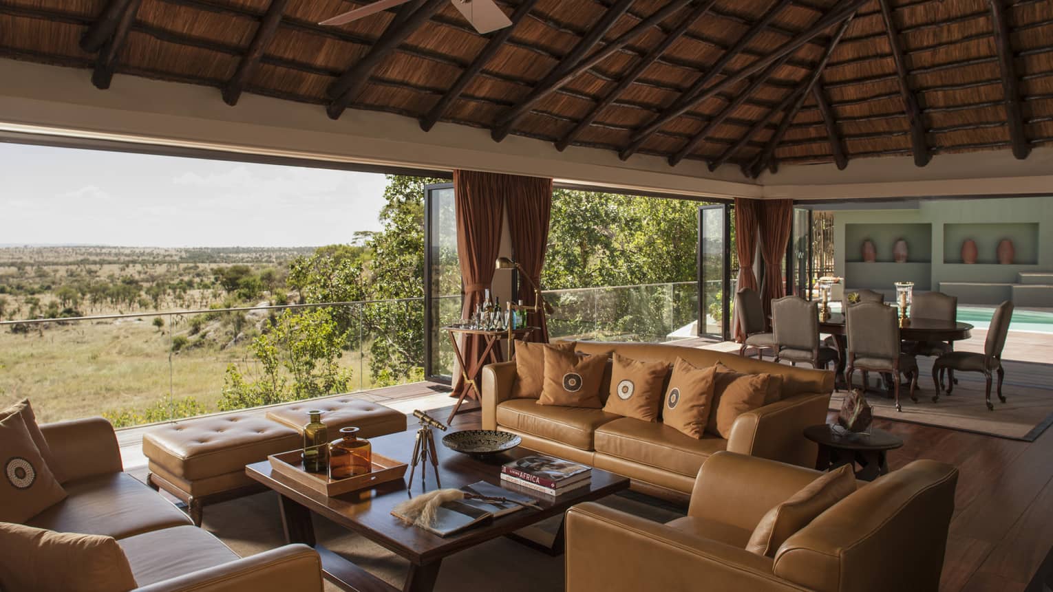 Presidential Villa tan leather sofas, chairs around table, large dining room, open wall