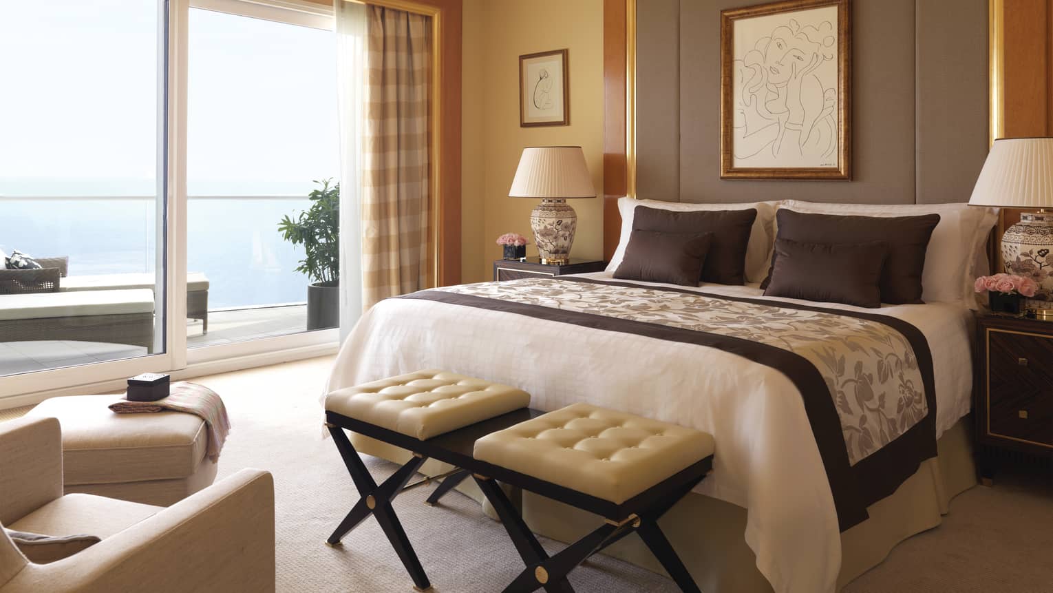 Diplomatic suite room with bed with tall upholstered headboard, bench with two white leather seats, white ottoman