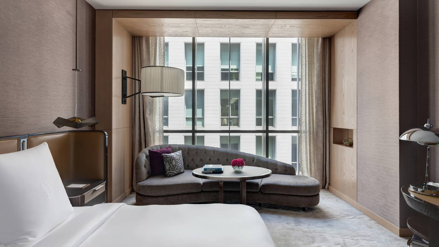 Bedroom with mauve-coloured walls, king bed, chaise lounge by window