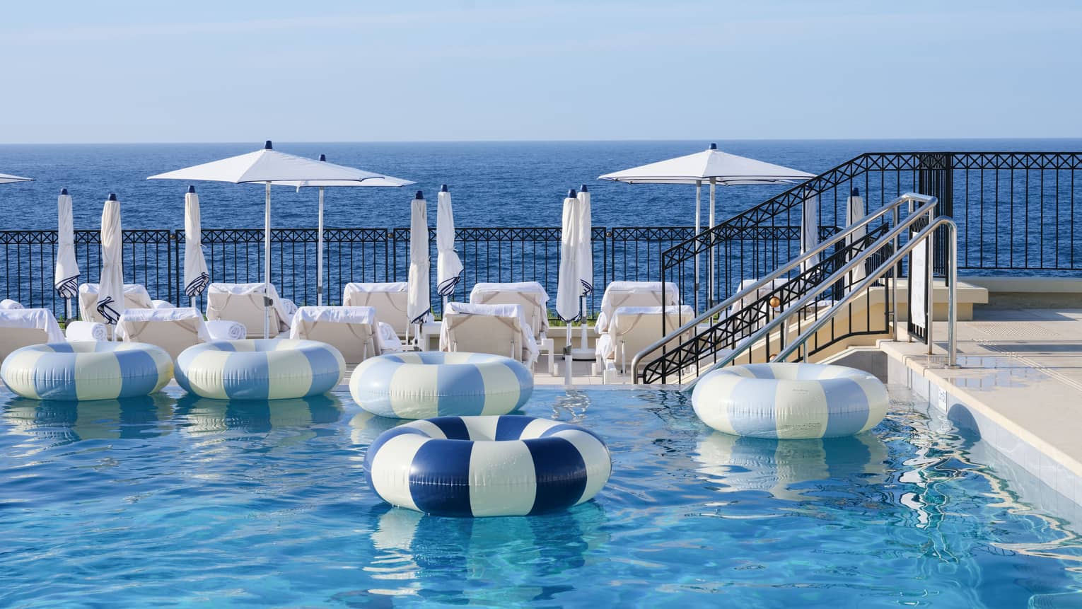 Inflatable blue-striped inner tubes drifting in luxury hotel pool