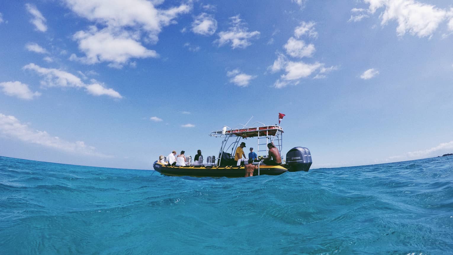 People sit on edge of small inflatable motor boat, prepare to snorkel