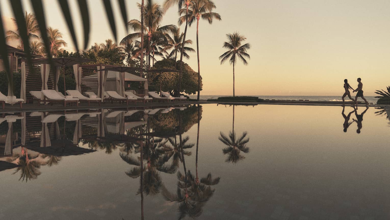A reflective pool at a tropical resort with beach in the distance