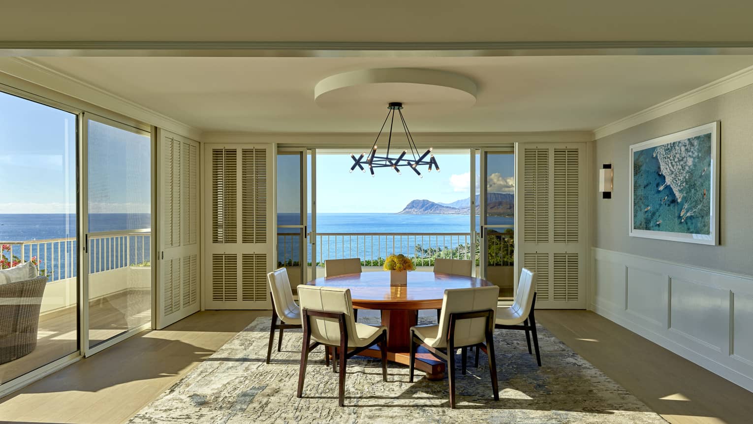 Dining room with round table and six chairs, opens to ocean-view terrace