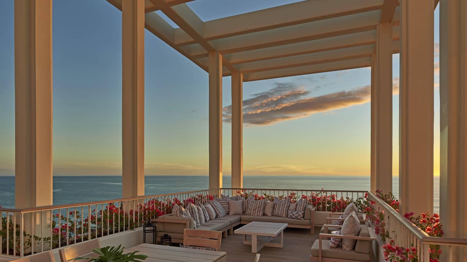 Large lanai overlooking the ocean with lounge furniture and pergola