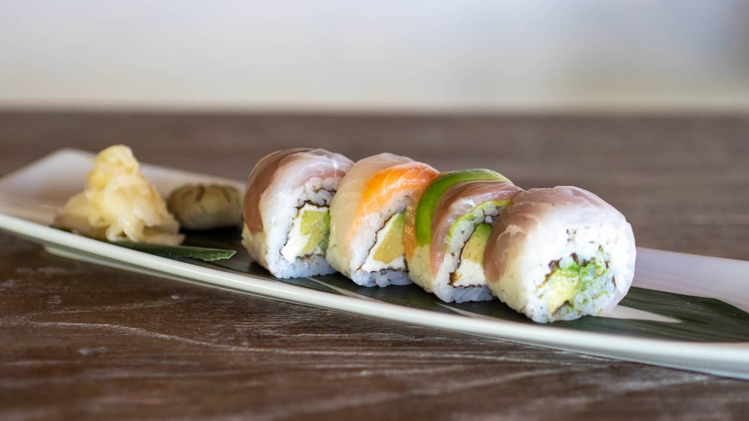 Colourful sushi on a white and black plate.