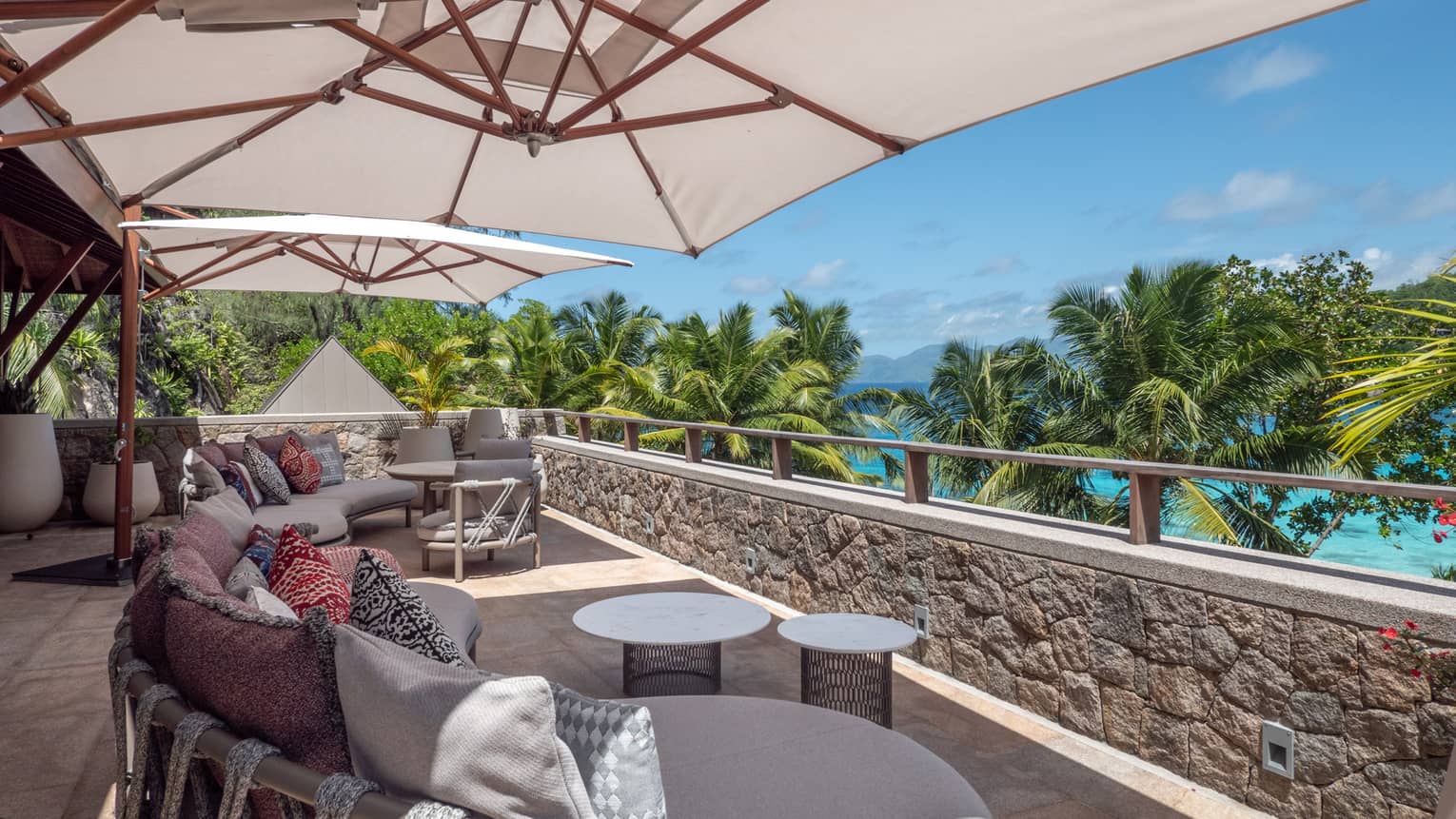 Outdoor lounge seating set under umbrellas on tropical sea-view terrace