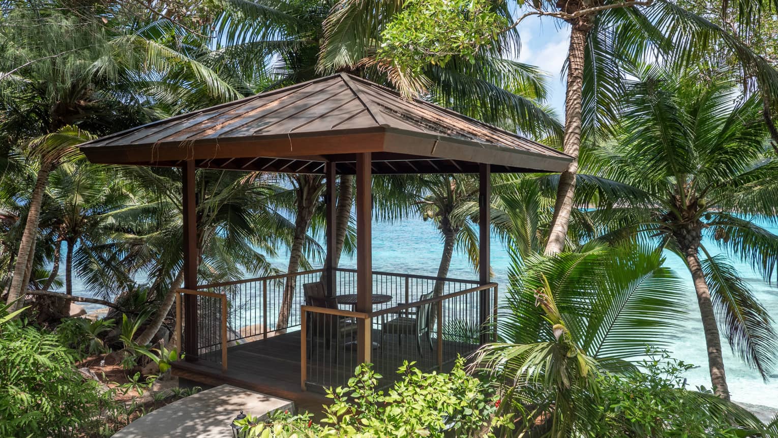 Small pavilion with a table and two chairs at a tropical point overlooking the beach