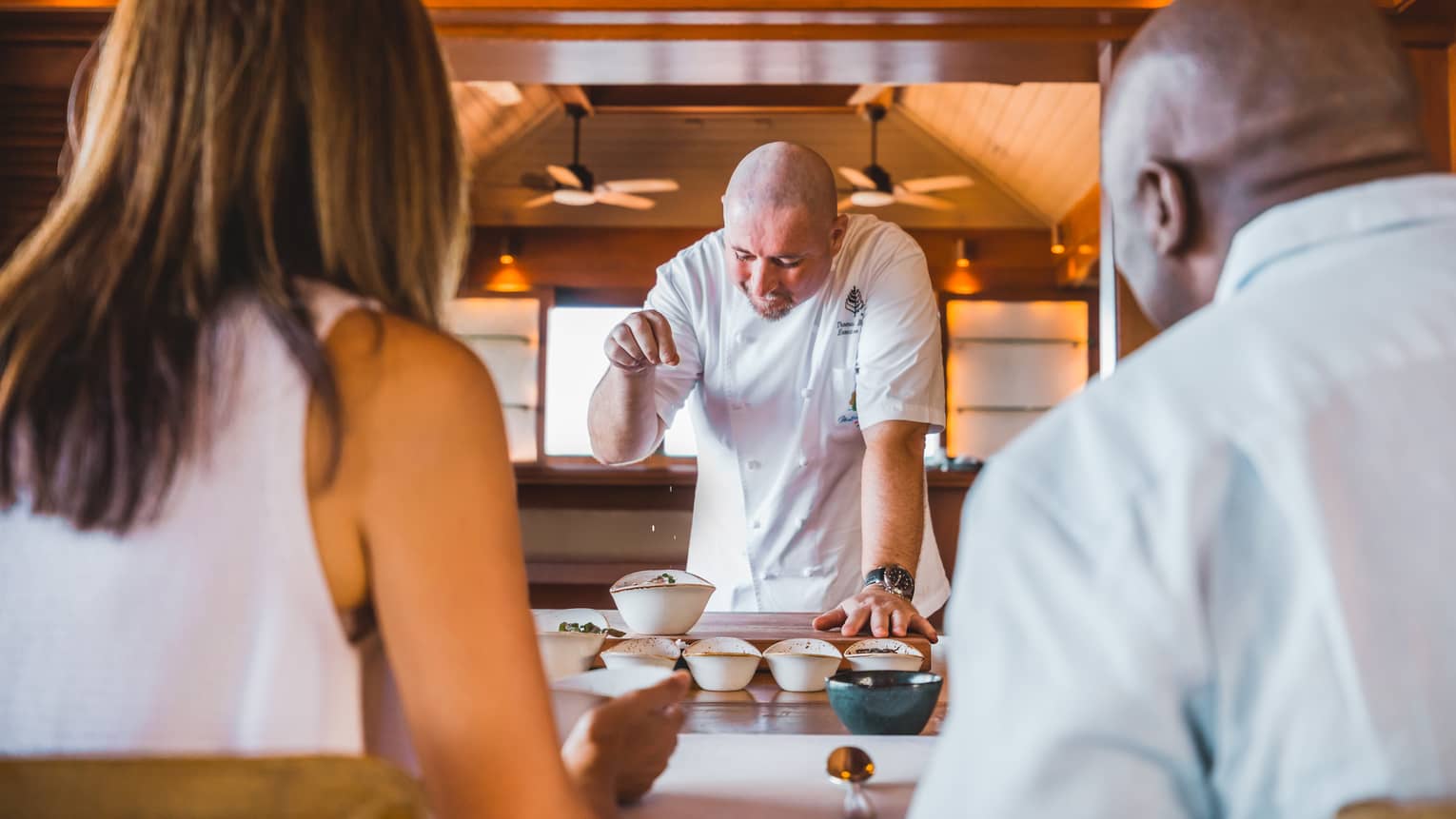 Guests watch as a chef sprinkles spices onto a special dish
