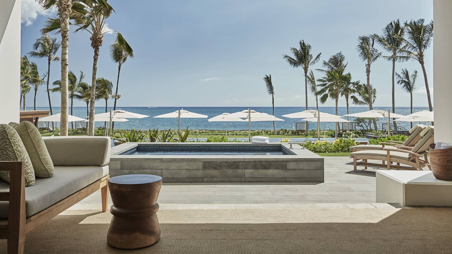 Pacific Suite open to wall to patio with stone plunge pool, lounge chairs, ocean views