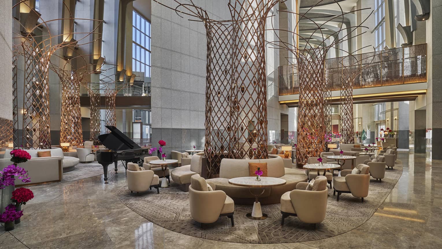 Lounge area set in hotel lobby with two-storey ceilings and tall, red wire scupltures