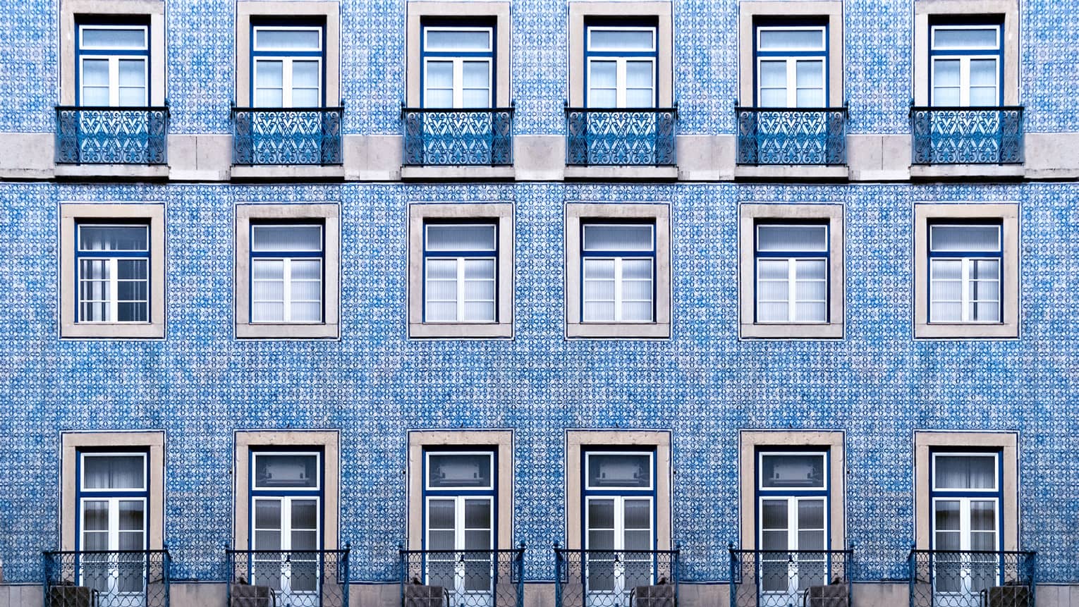 A blue tiled wall with many windows and balconies.