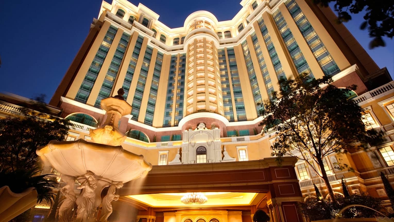 White stone fountain outside Macao Cotai Strip Four Seasons Hotel entrance, lights at dusk
