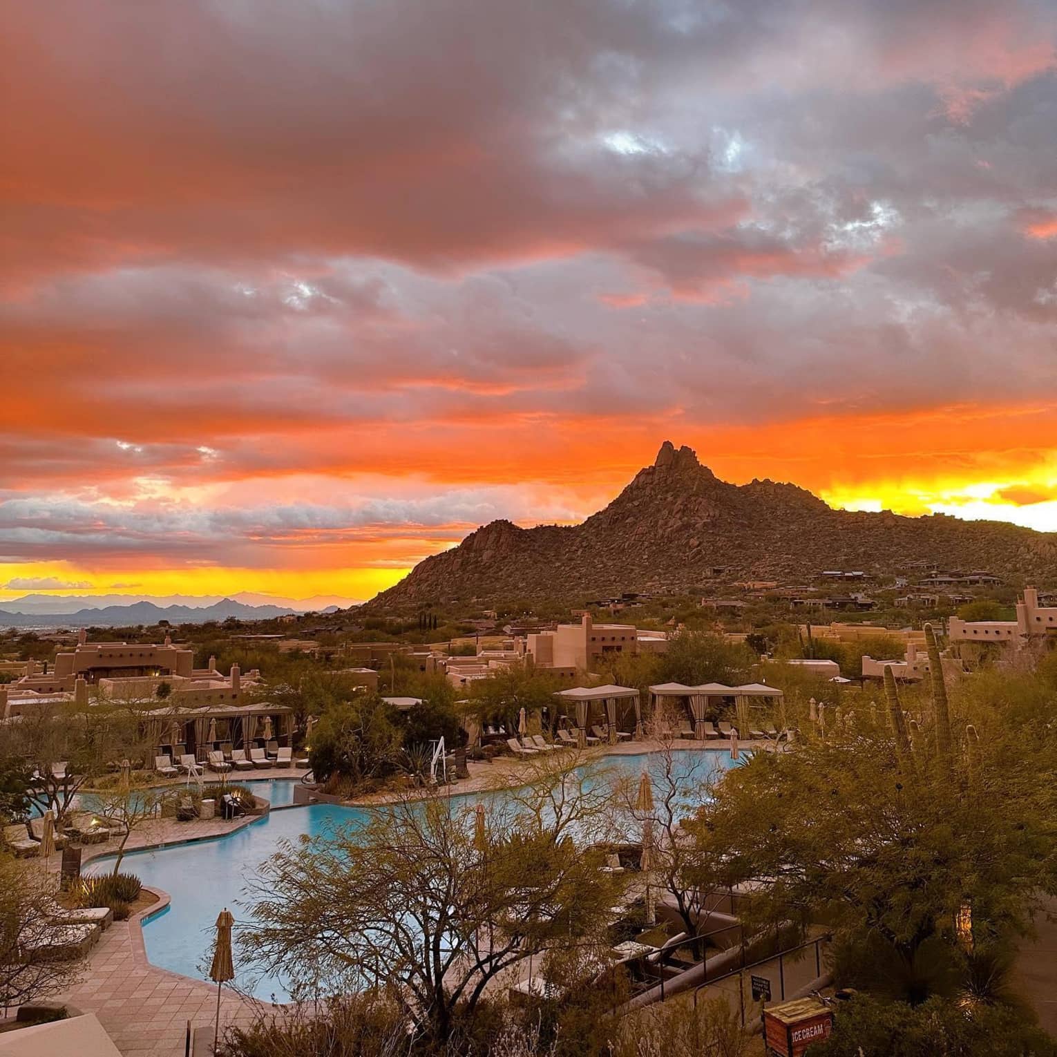 Exterior view of a pool, cabanas and villas at Four Seasons Resort Scottsdale at Troon North, with mountains and sunset behind