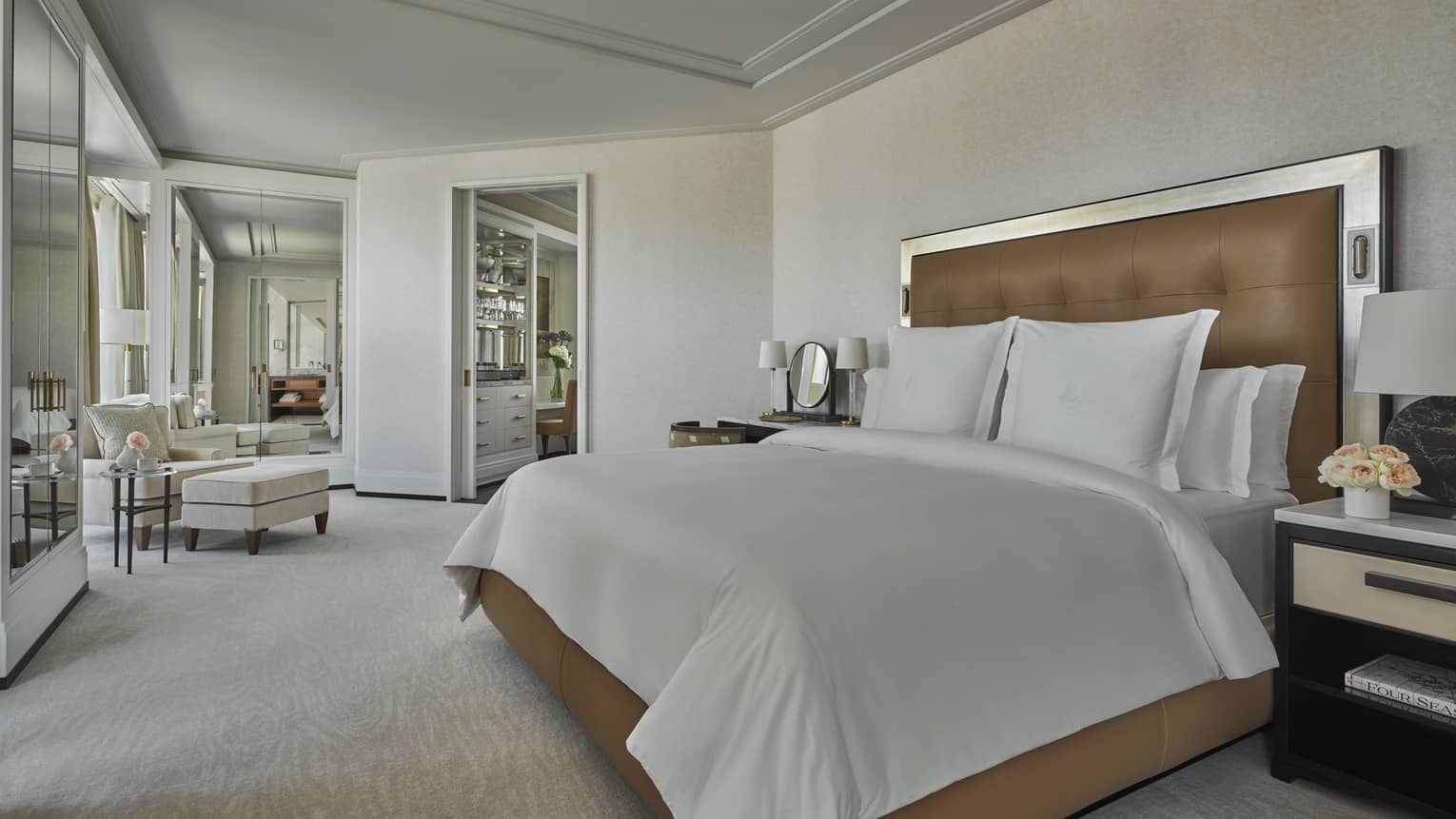 Bedroom with leather bed frame, white sheets, cream carpet and walls