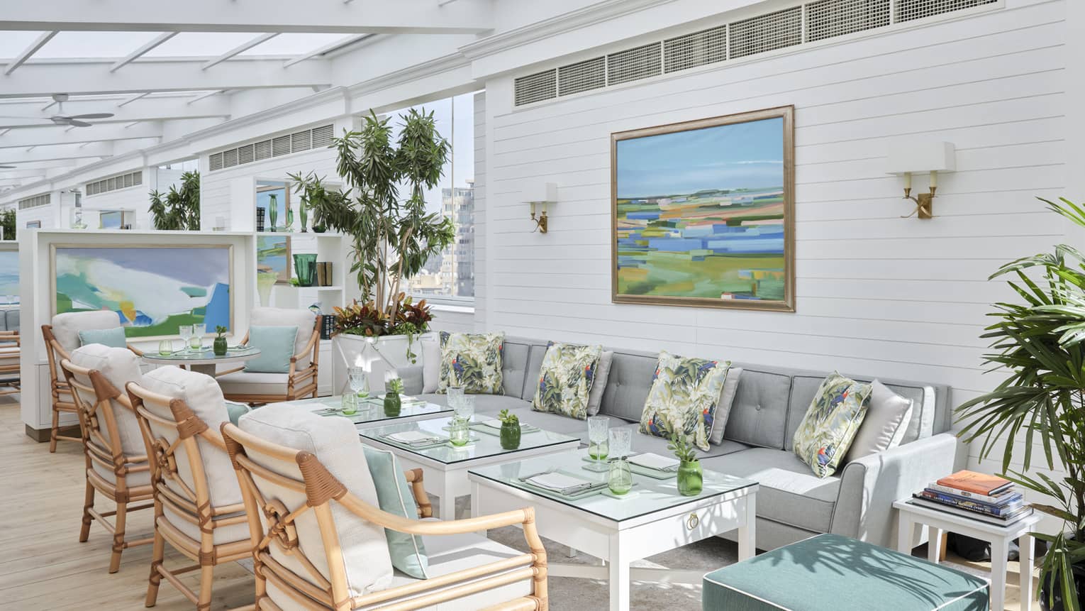 Newly renovated Upper Deck Lounge dining room with blue and green colour scheme, grey sofa, rattan chairs, potted plants