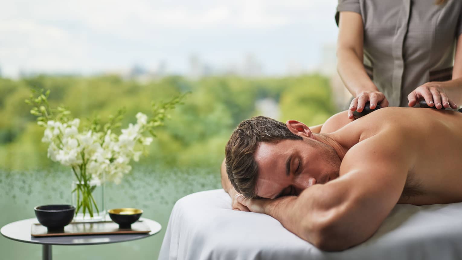 A man receives a massage next to a pond.
