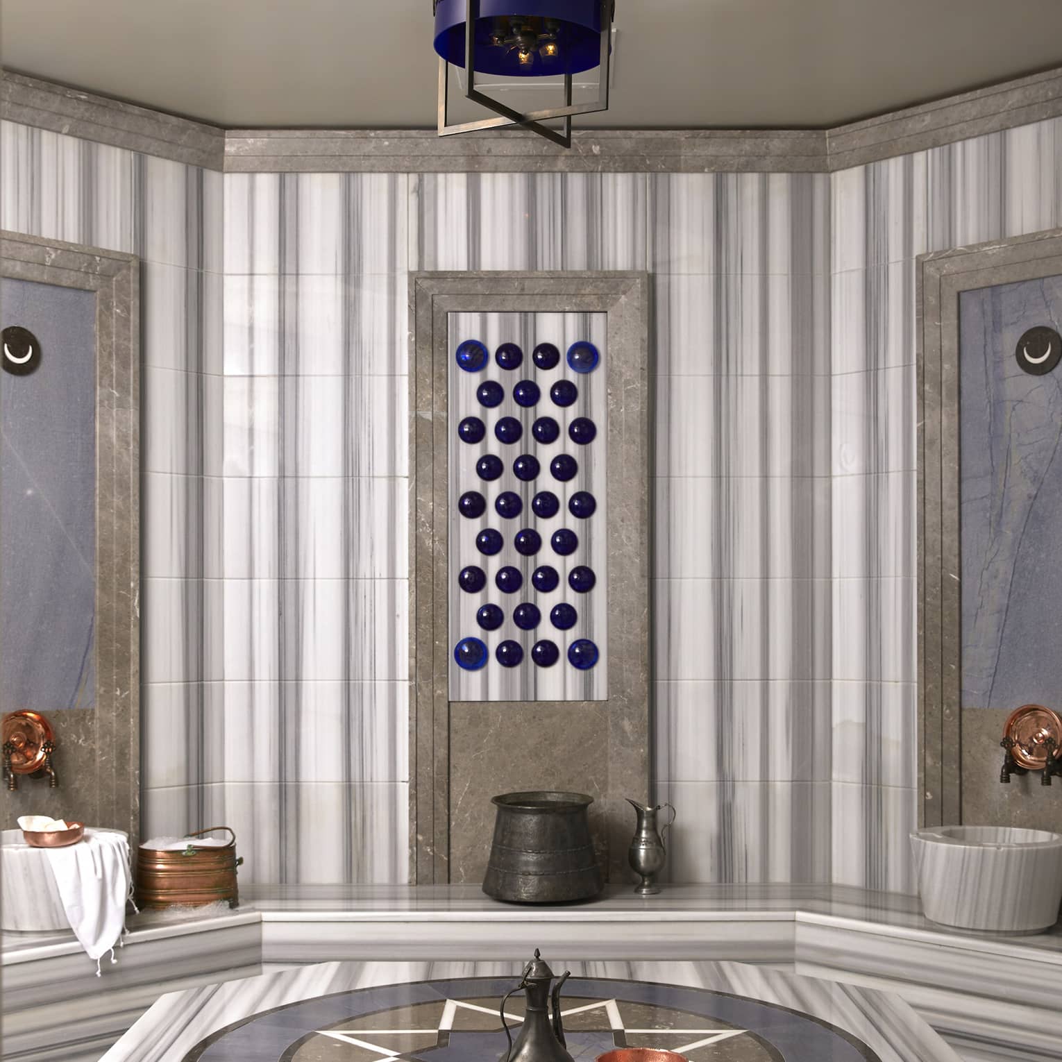 Rolled towels and kettle on marble bench in Turkish Hammam spa room