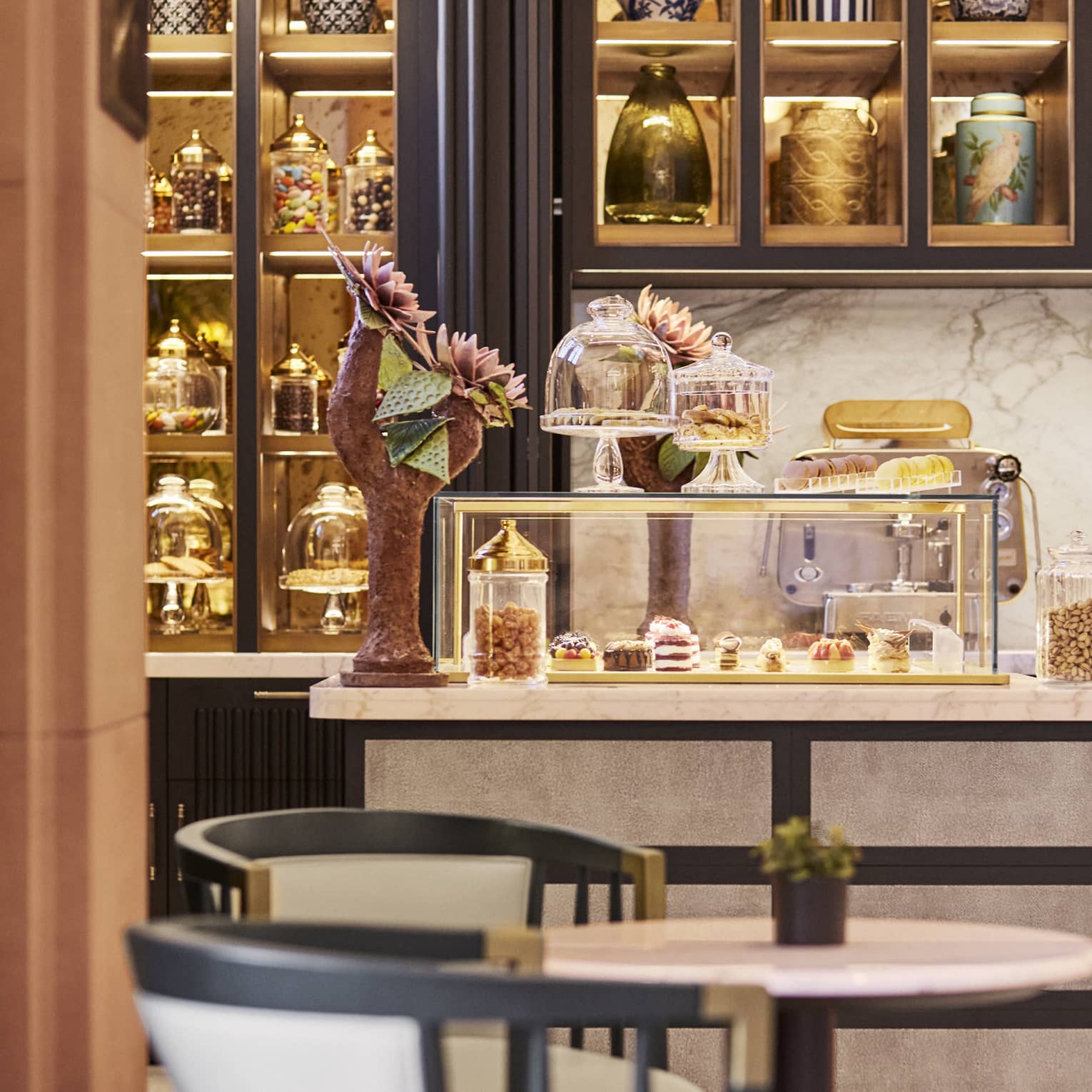 La Pistache cafe table by counter with glass display, gold shelves