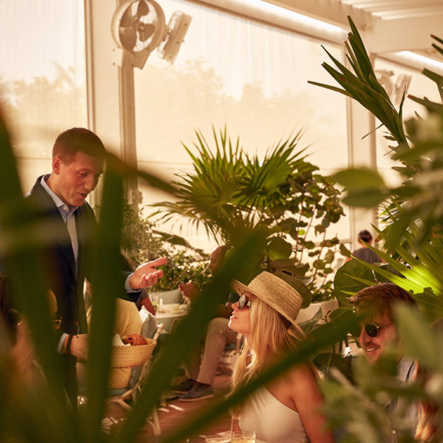 A woman being served food in a covered eating area with plants.