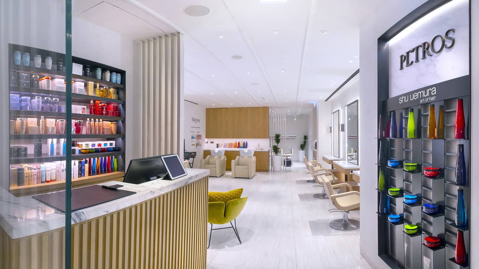 Petros Hair Salon reception desk with hair products on wall and view into salon