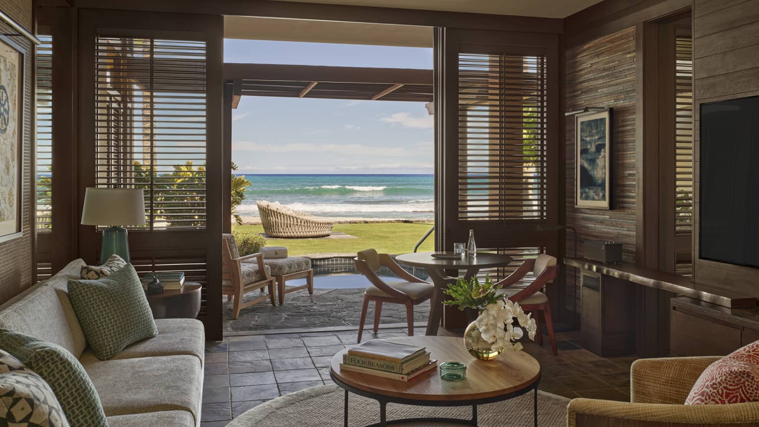 Living room in resort suite, opening to private terrace with ground-level beach view