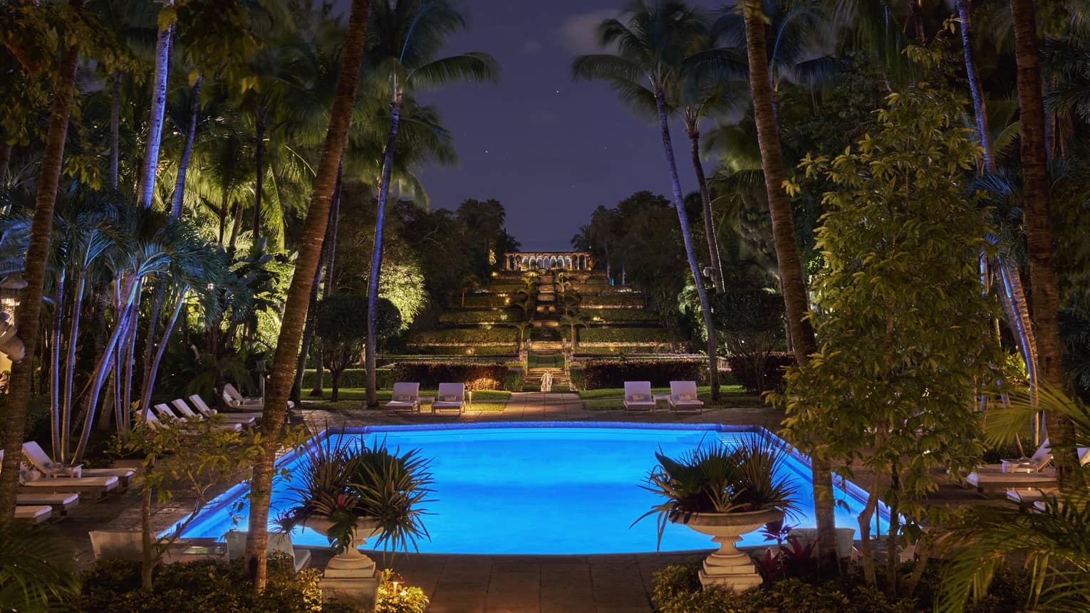 An outdoor pool lit up with lights at night.