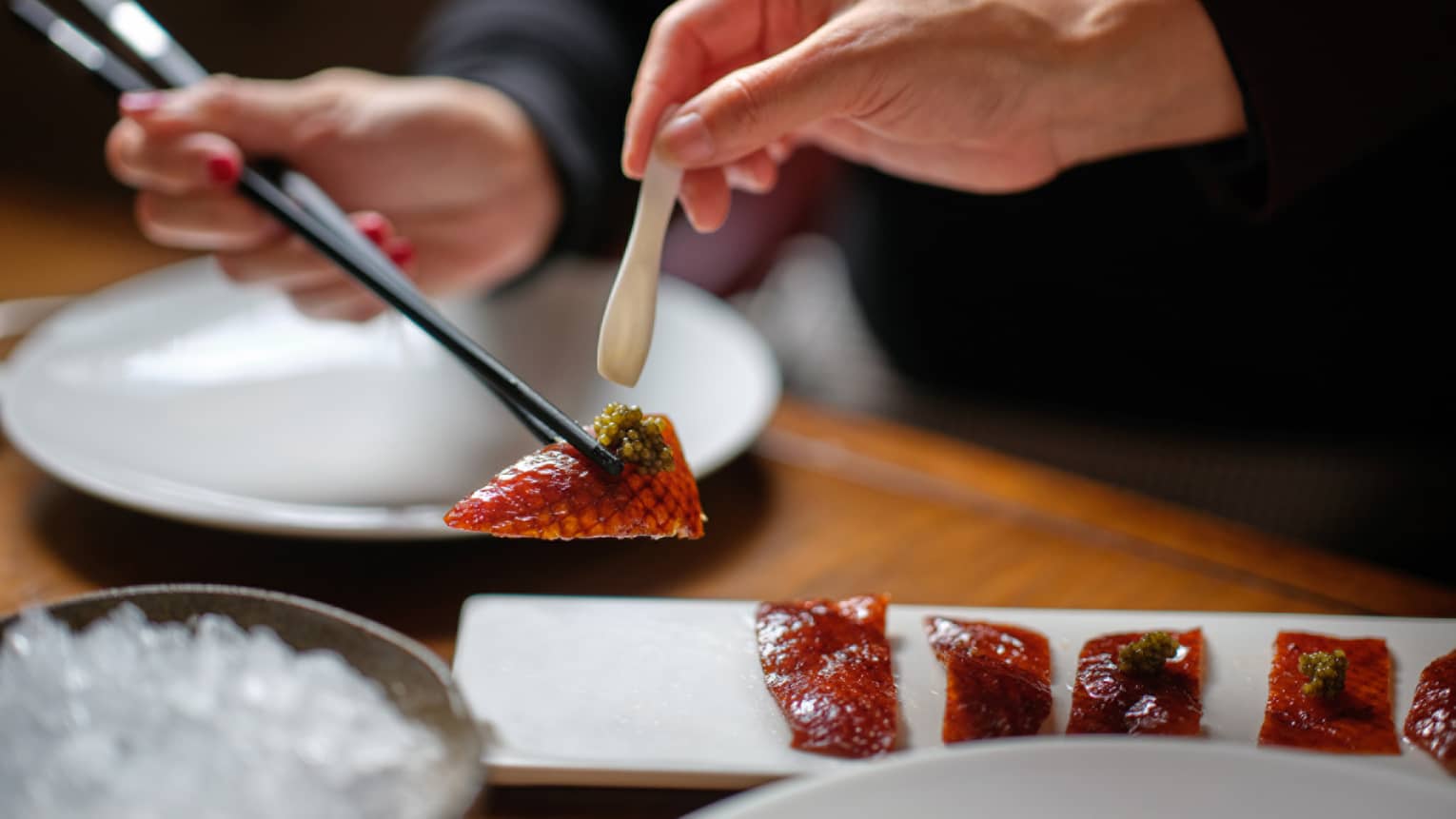 Peking duck being held by chopsticks.