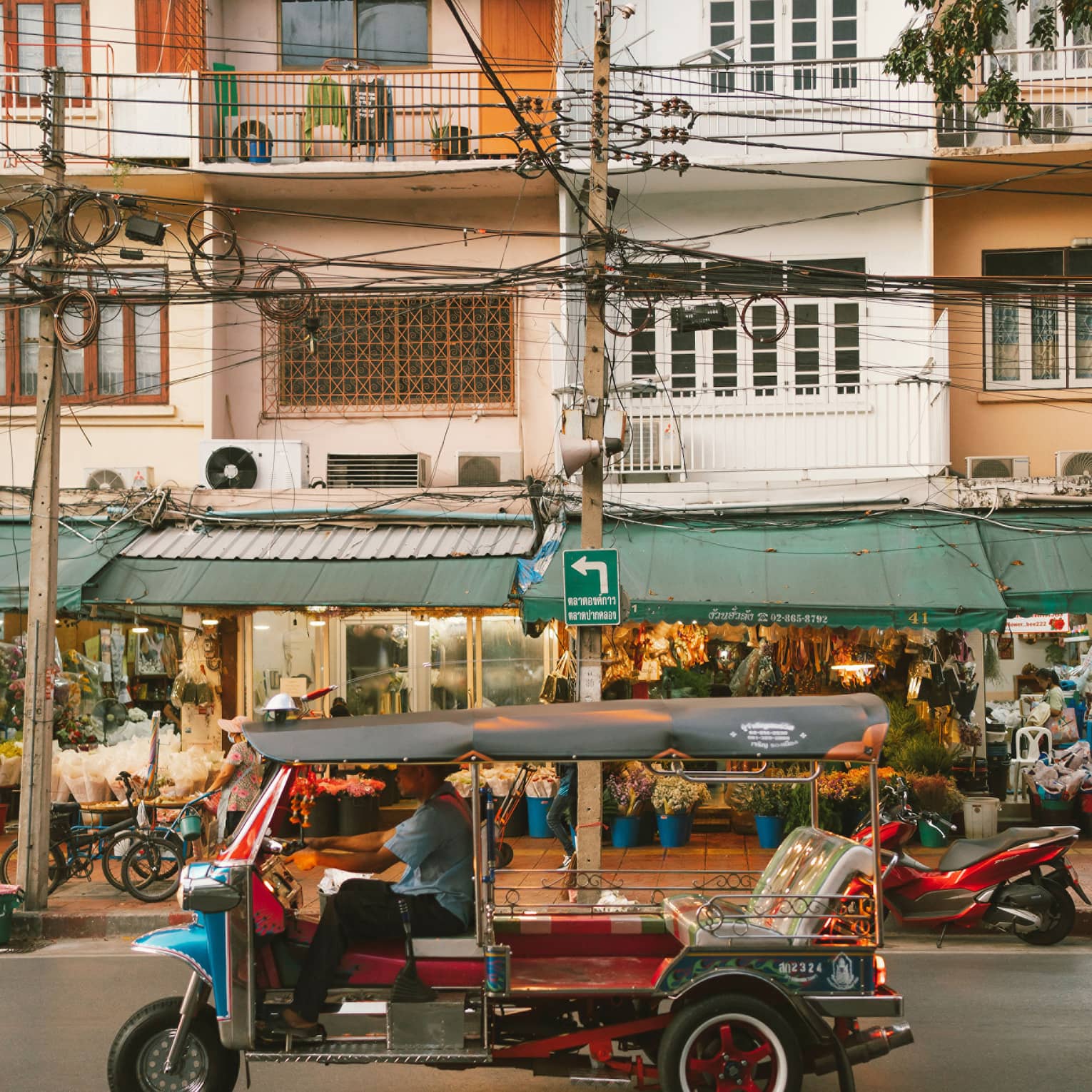 Colourful auto rickshaw parked in front of three-storey building with green awning