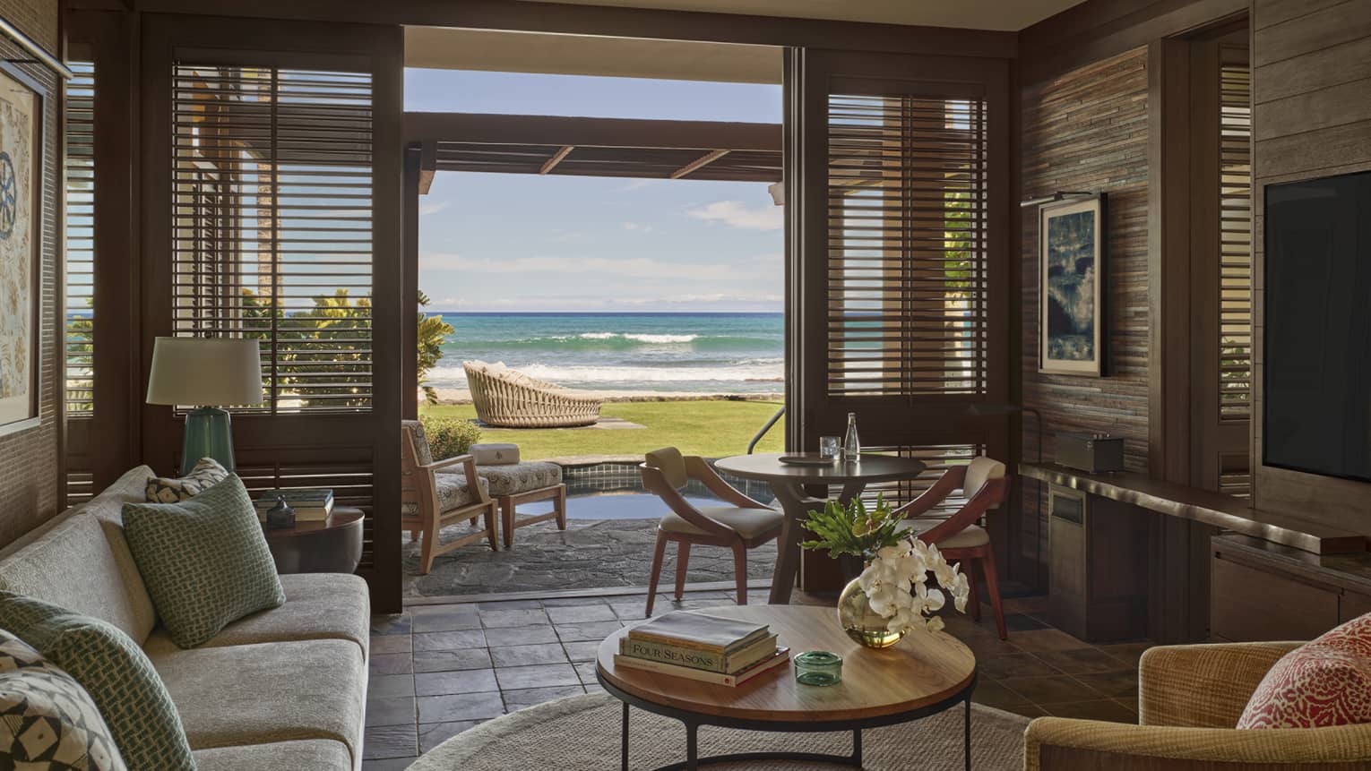 Living room in resort suite, opening to private terrace with ground-level beach view