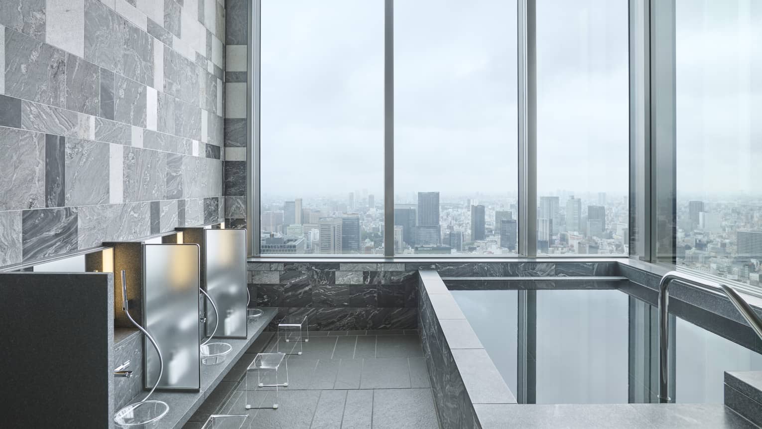 Japanese Ofuro corner bath with floor-to-ceiling windows overlooking the city