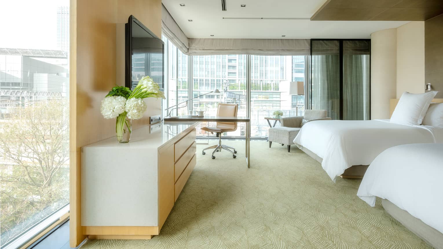 Deluxe Premier Twin Room with desk area and floor-to-ceiling corner windows looking out onto the city skyline