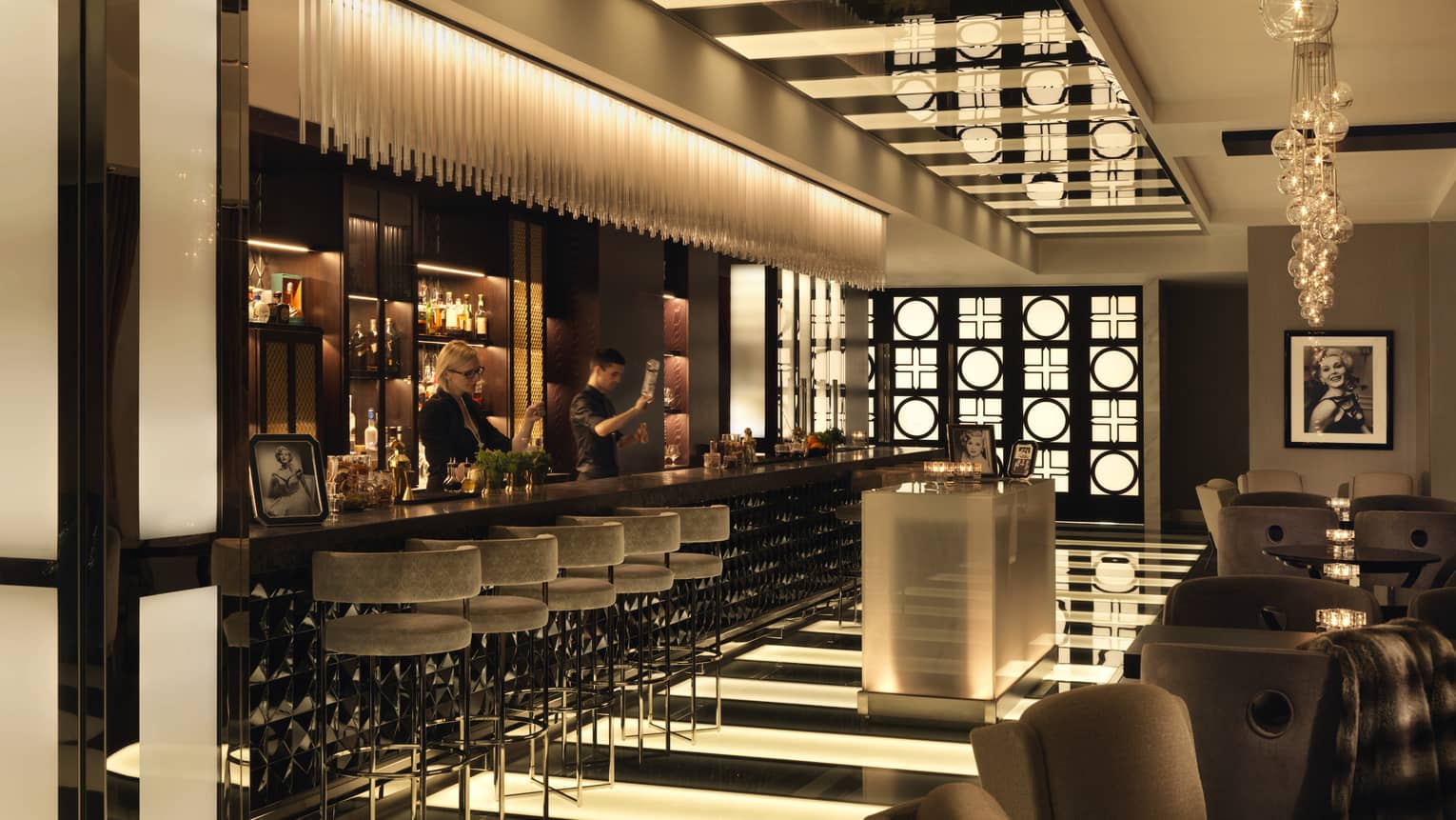 A view of a bar with pin-striped floors, a crystalline set of lights and several booths.