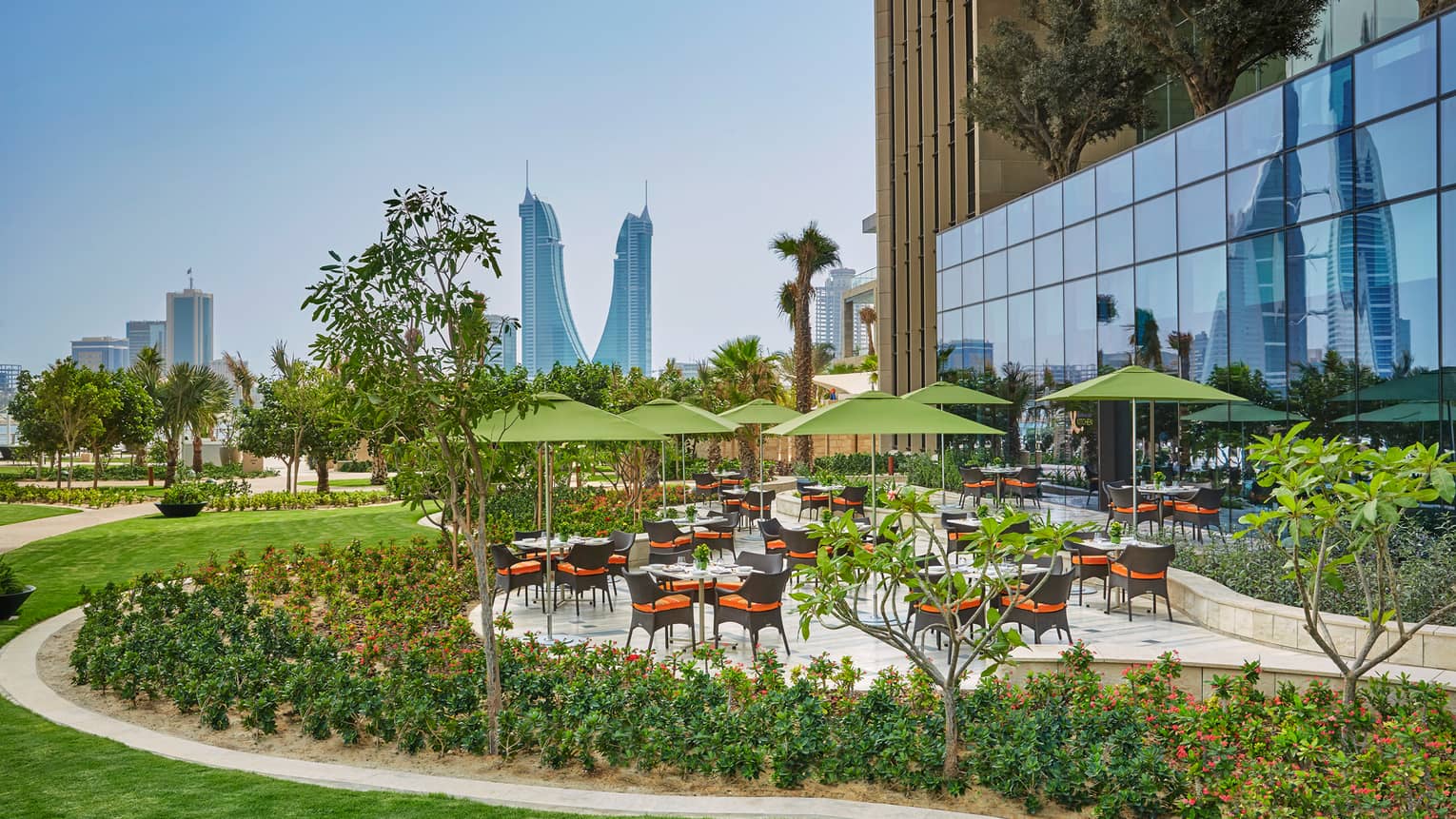 Bahrain Bay Kitchen outdoor patio tables, umbrellas, surrounded by green gardens, lawn