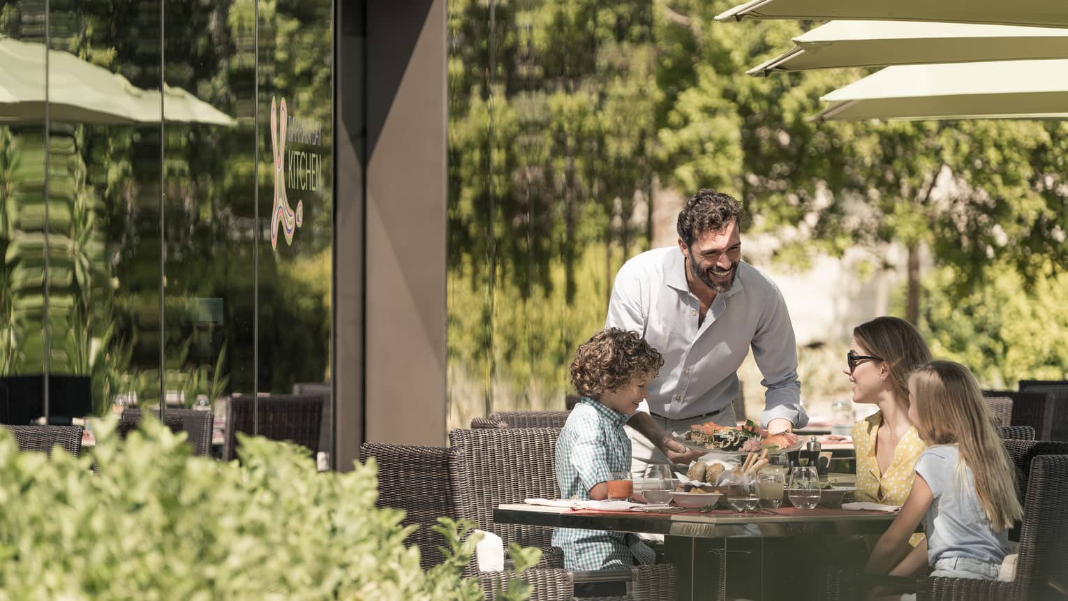 Family of four smiling at outdoor patio table over a meal