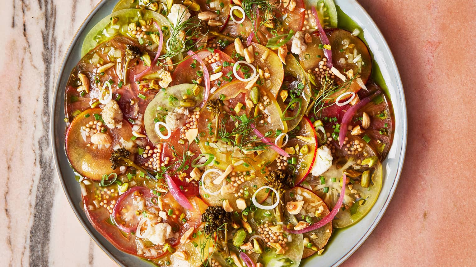 A plate of thinly sliced fruit and vegetables with spices.