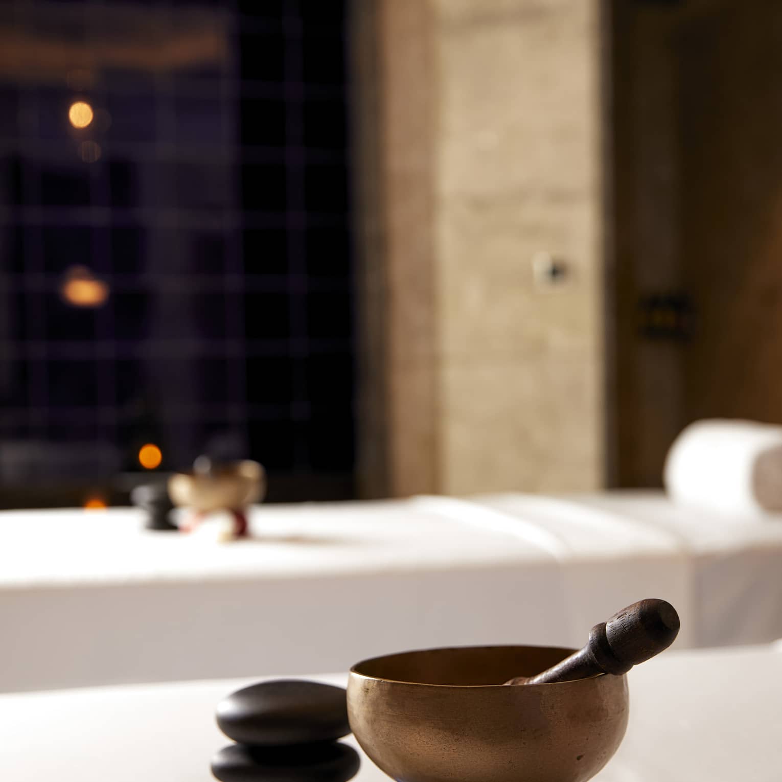 Copper bowl and wood spoon on couples spa treatment beds in spa