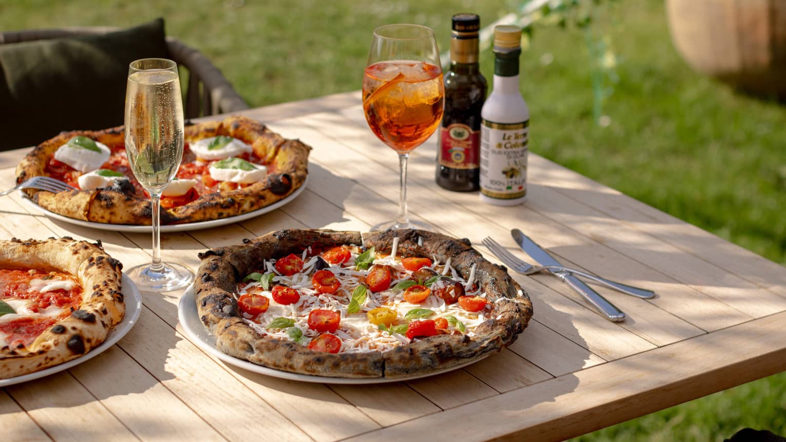 Homemade pizzas set on outdoor teak dining table