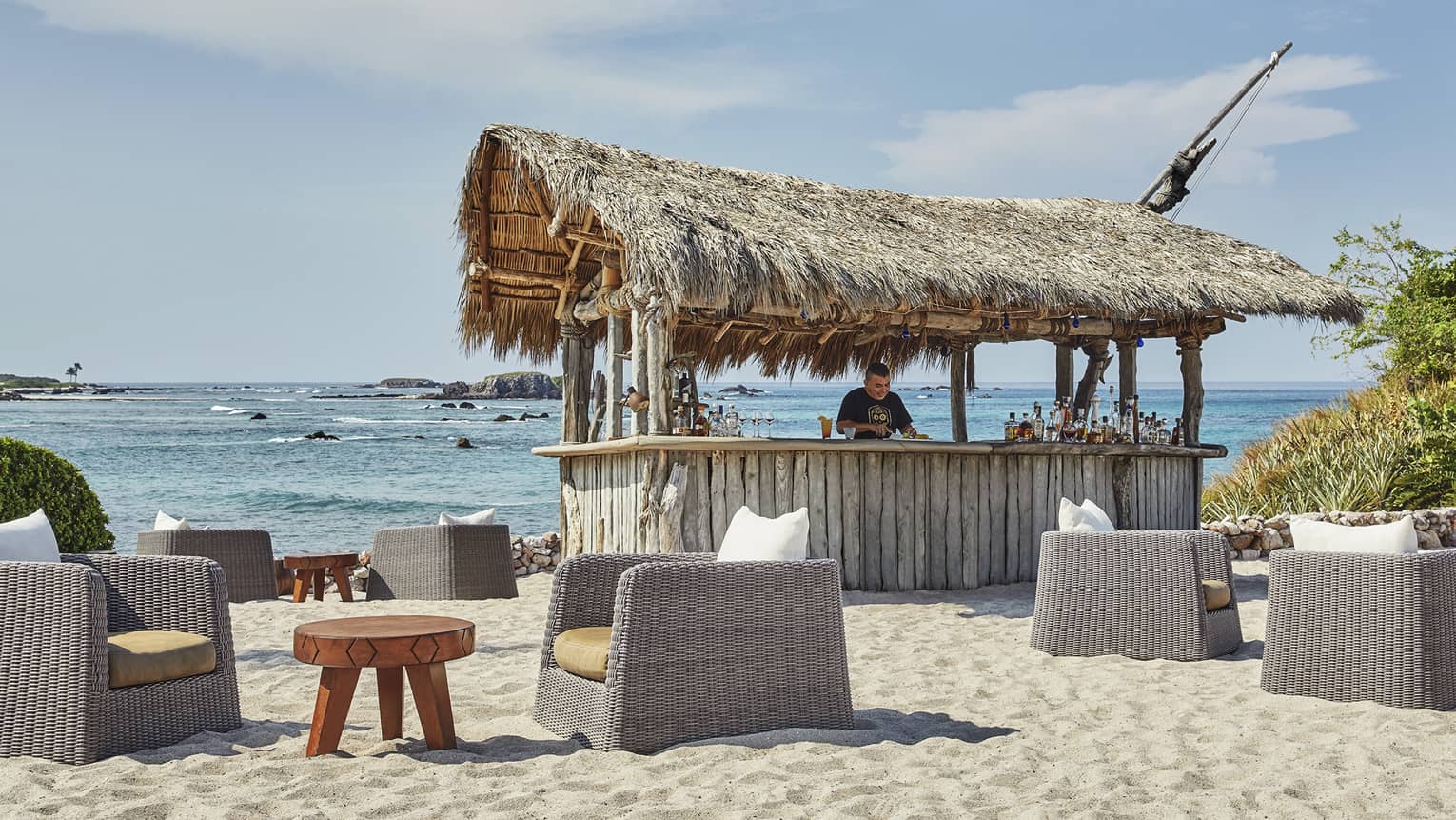 A man works at shack bar on the beach, with the water in the background